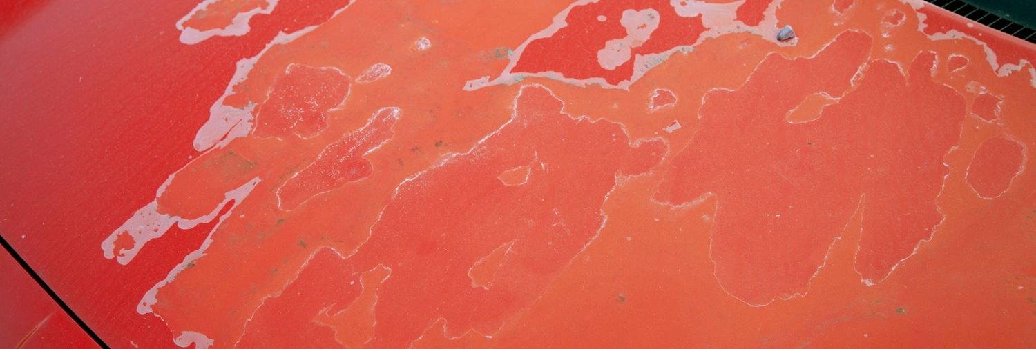 peeling paint on the hood of a red car