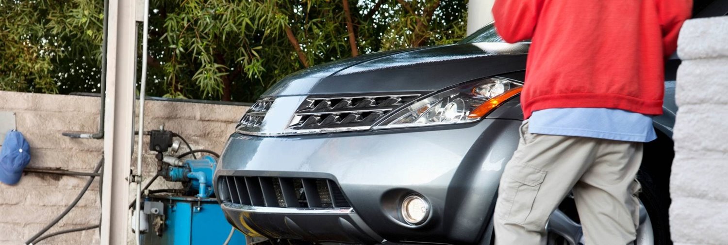 front of silver suv emerging from car wash tunnel with an employee standing by