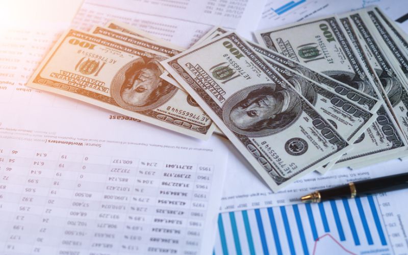 several $100 bills laying on top of paper reports