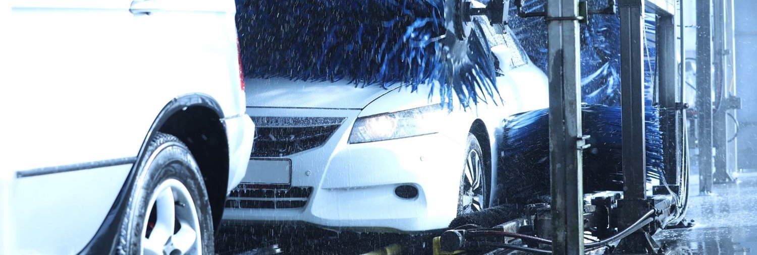 white sedan going through car wash as top wrap cleans the hood