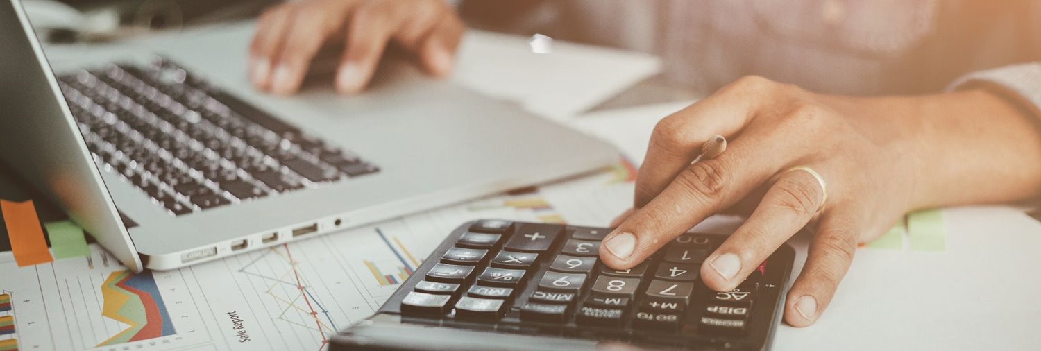 close up of someone's hands using a keyboard and calculator on top of printed reports