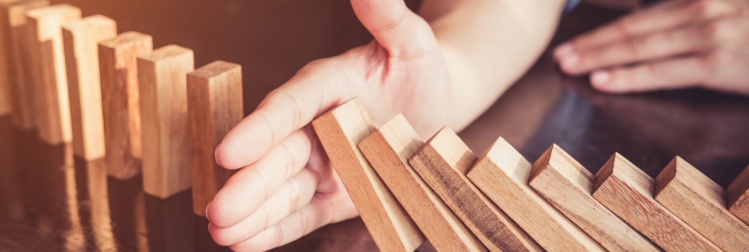 falling dominos on a table stopped by a human hand