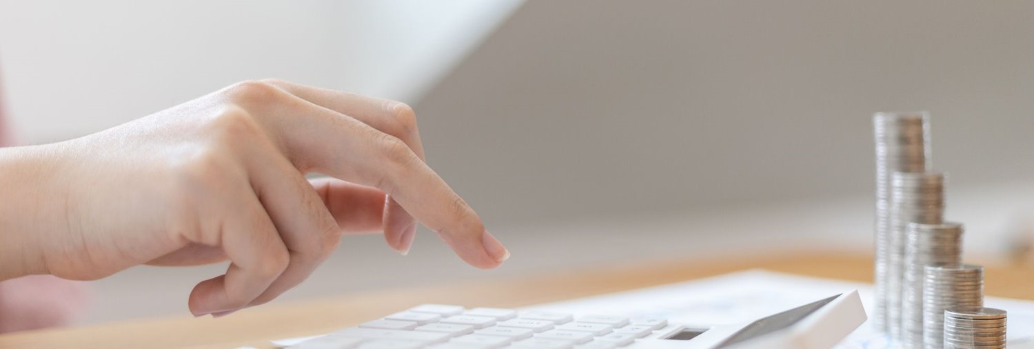 hand using a calculator with gradually increasing stacks of coins nearby