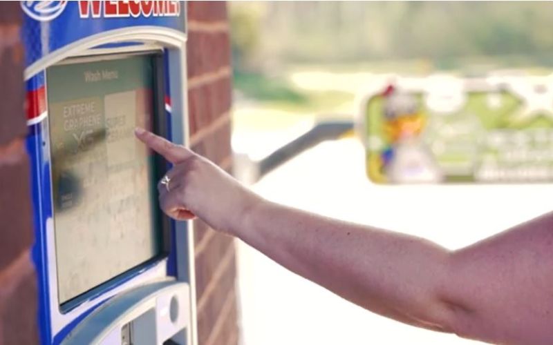 proxy_members.jpg woman's hand reaching to touch a car wash pay station screen