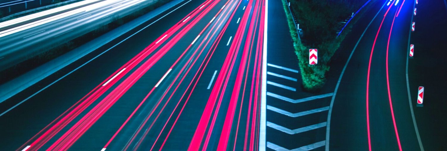 highway at night with an off ramp with lines that appear to be blurred speeding cars