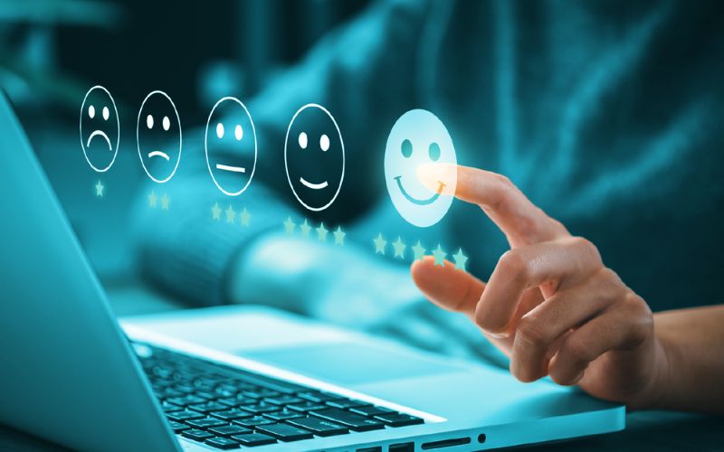 responding_to_customers_online.jpg person sitting at laptop pointing at a graphics in the foreground of rating faces