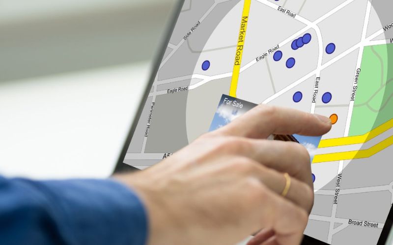 A hand pointing at a computer screen displaying a map