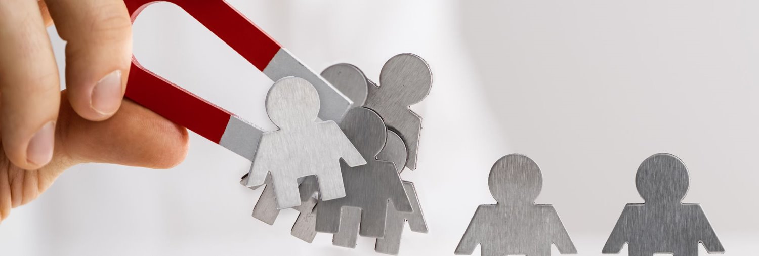 hand holding magnet attracting metal figures of people