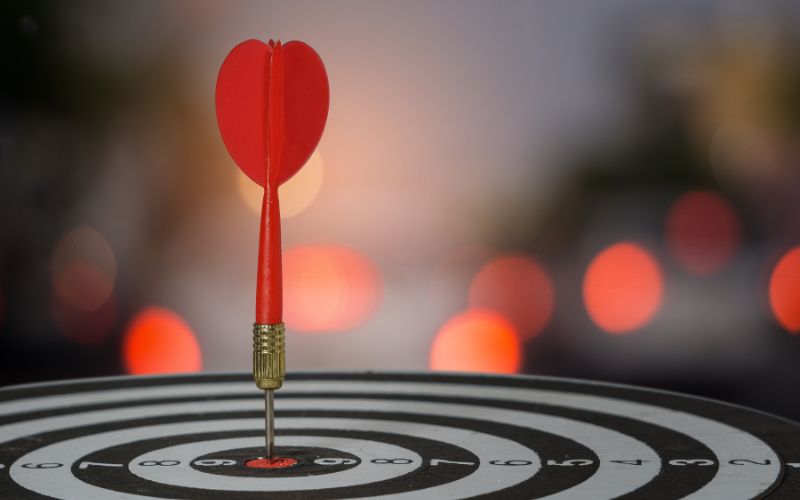 dart board laying on a flat surface with a dart sticking straight up in the bullseye circle