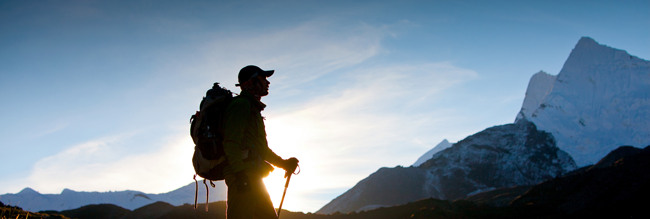 man looking up at snow covered mountains in sunrise